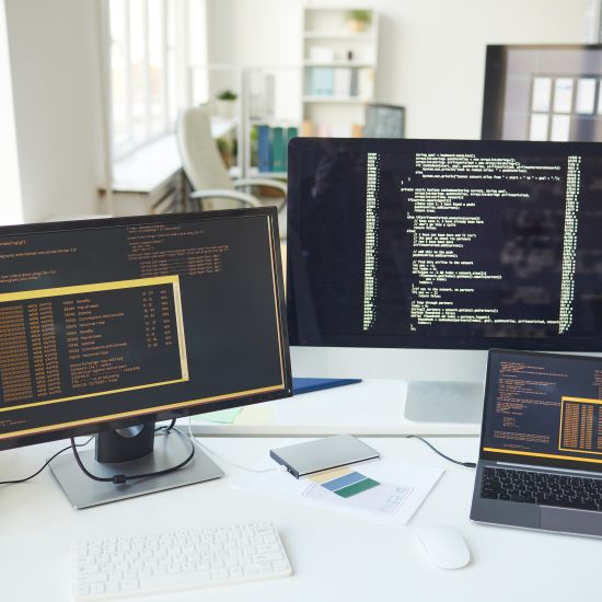 Three computer screens of different sizes showing code